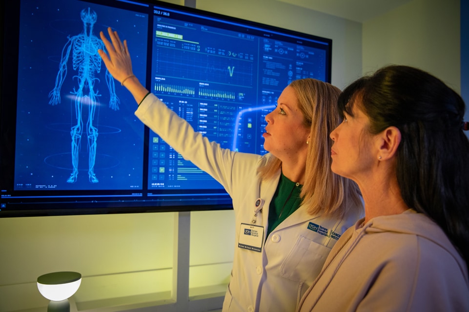 a female tgpn provider examines breast cancer radiology images on a touch screen monitor with a female patient