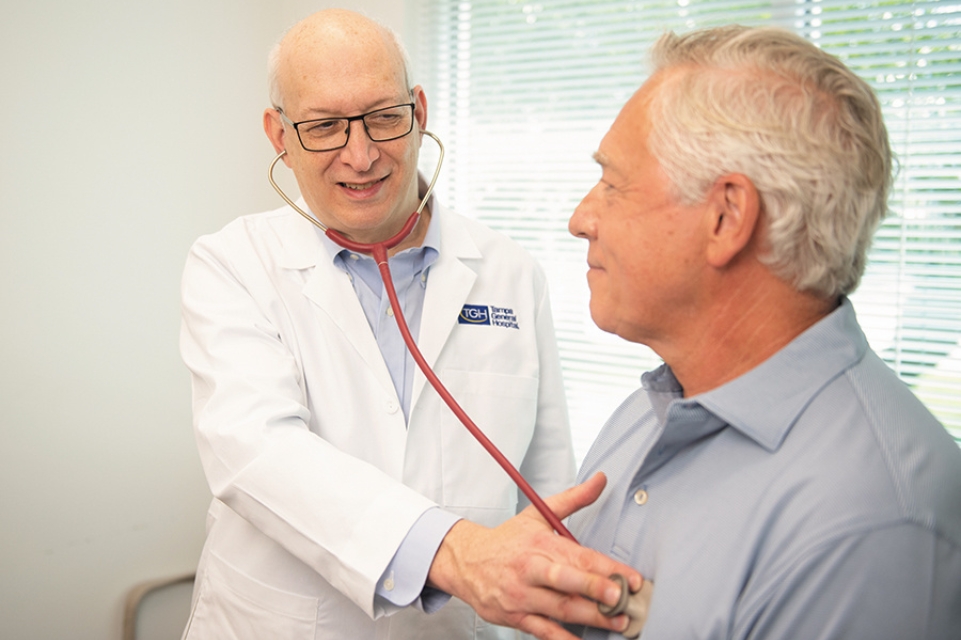 tgh physician dr glenn englander listens to an older male patient's breath with a stethoscope