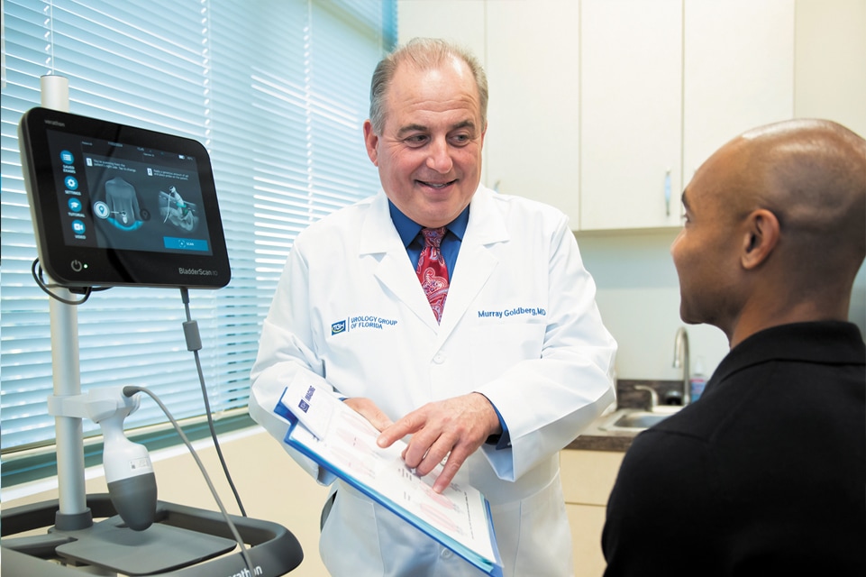 dr goldberg of urology group of florida reviews a patient chart with a male patient in his office