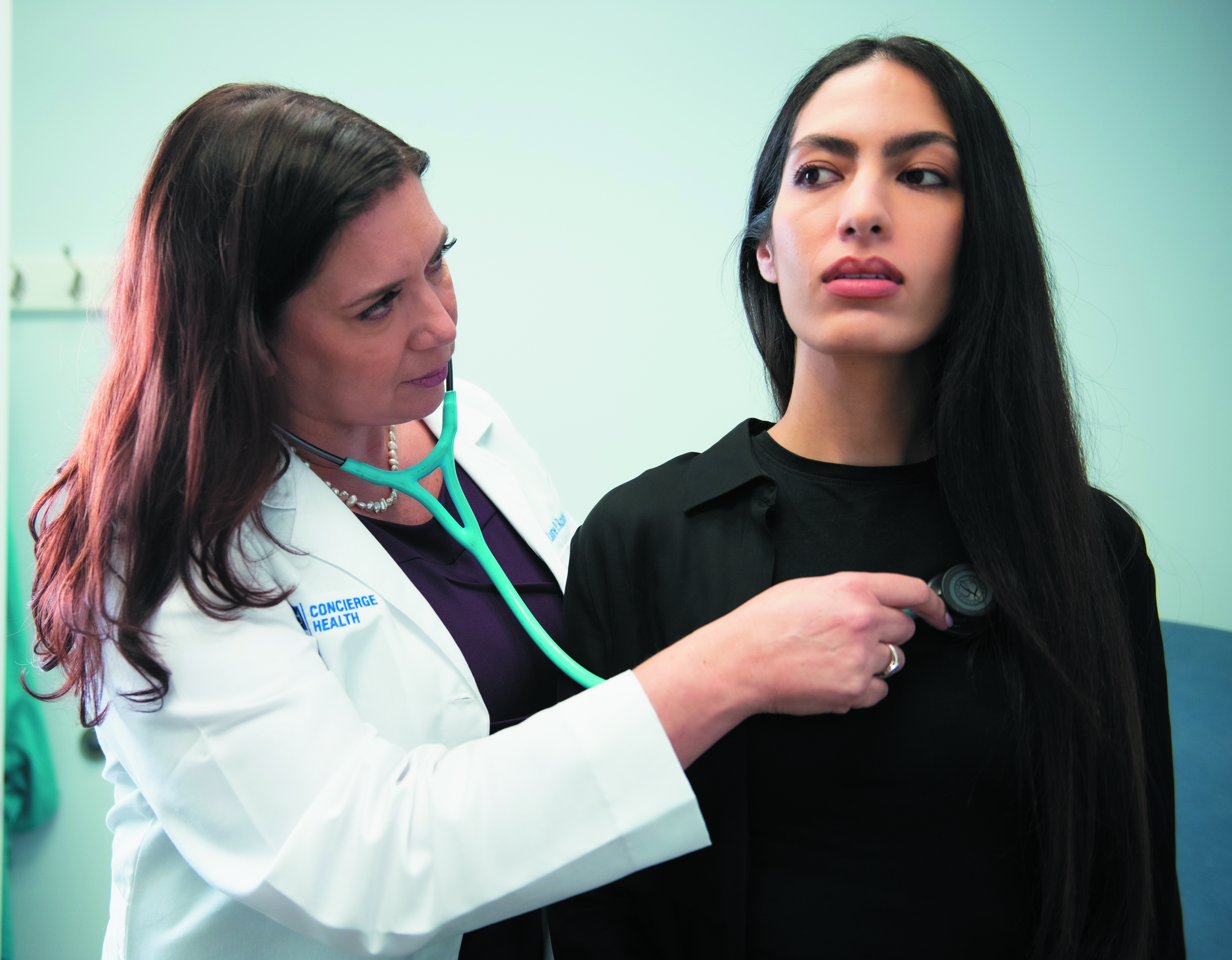 concierge health provider dr rothman checks a female patient's heartbeat with a stethoscope