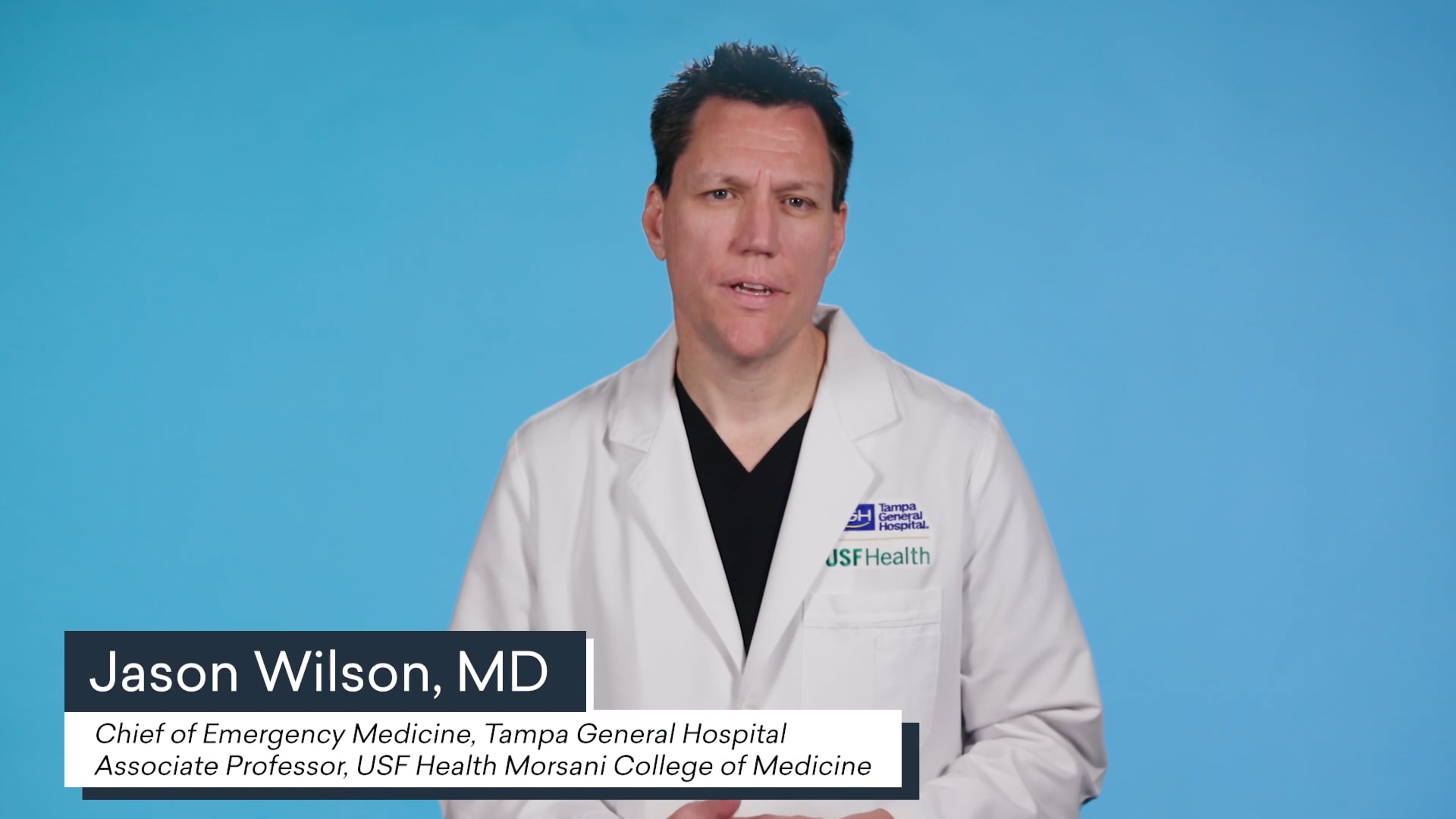 jason wilson md speaking in front of a light blue background with text jason wilson md chief of emergency medicine tampa general hospital associate professor usf health morsani college of medicine