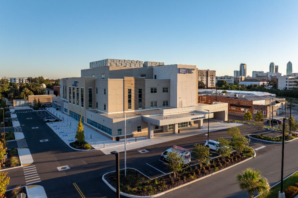 A photo of the four-story TGH Behavioral Health Hospital with the downtown Tampa skyline in the background.