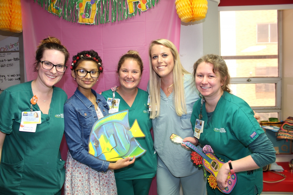 Teen girl posing with physicians after ringing the chemo bell
