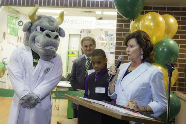 USF Bull mascot looking on as woman gives a speech