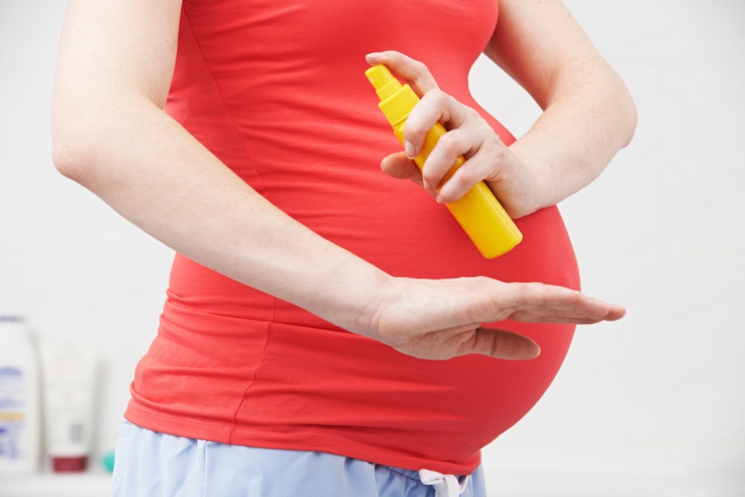 Pregnant woman applying sunscreen