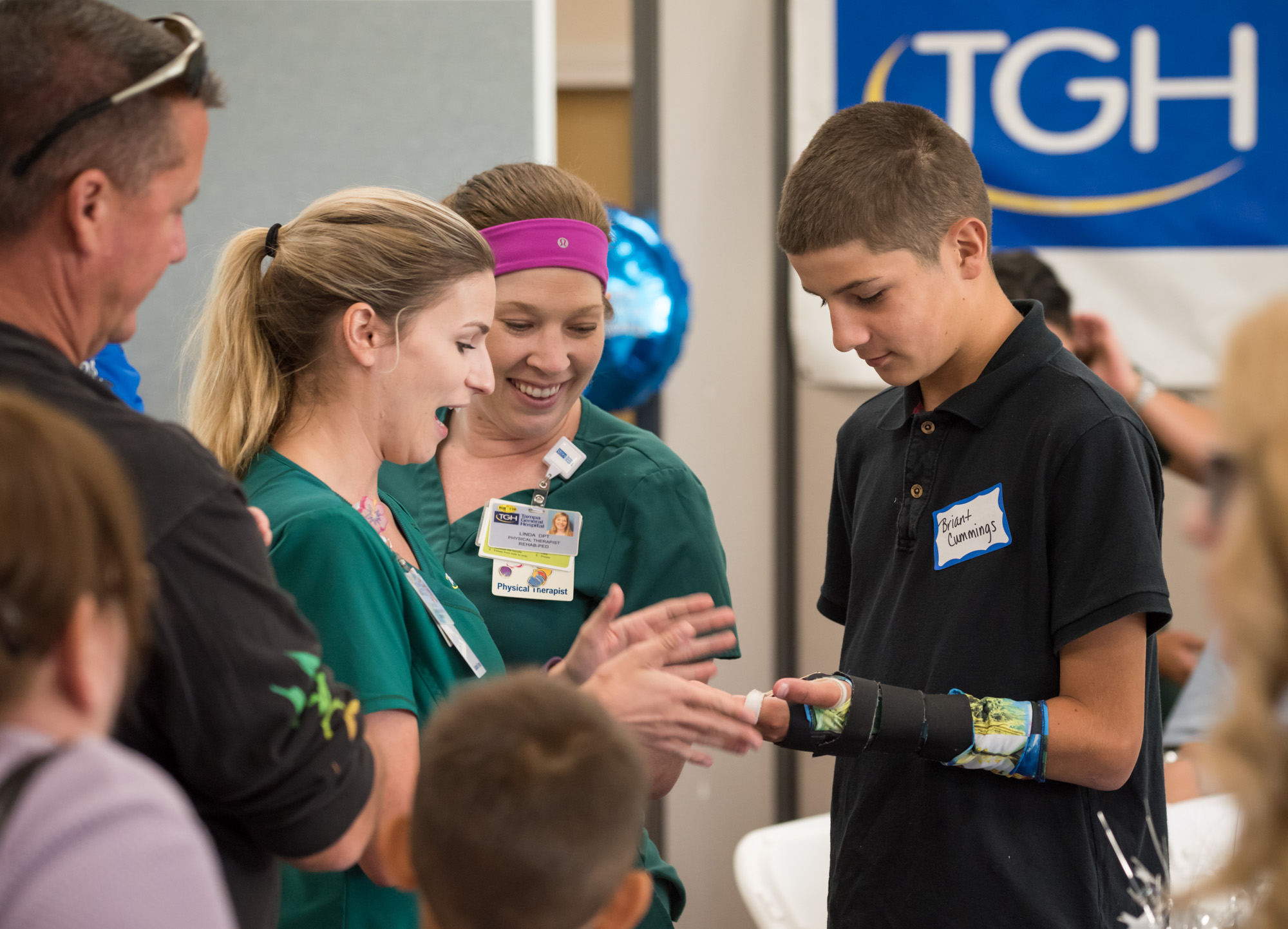 Two physical therapists looking at a young boy's injured arm at the trauma awareness luncheon