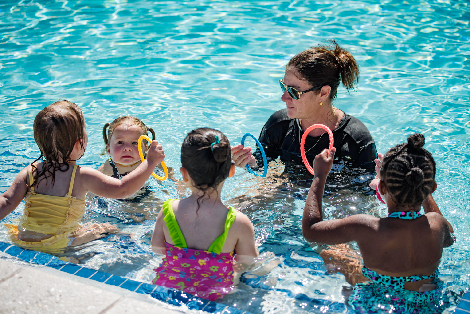 Woman teaching a group of young girls how to swim