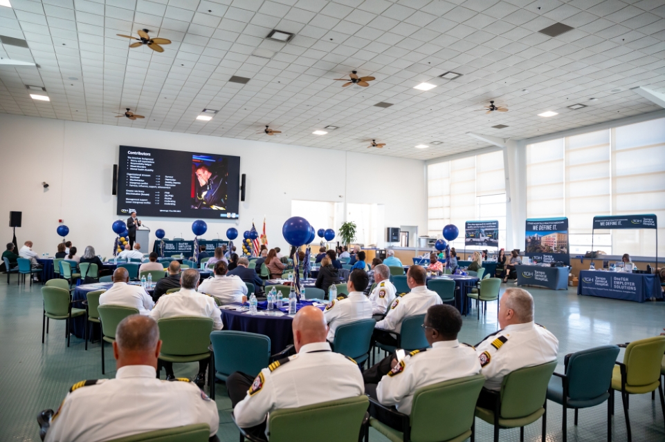 members of the tampa fire department attending a onetgh employer solutions workshop in a large banquet hall with decorations and presentation materials on a large screen