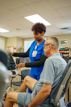 tgh pulmonary rehabilitation elderly male patient exercising on stationary bike while a female nurse assists