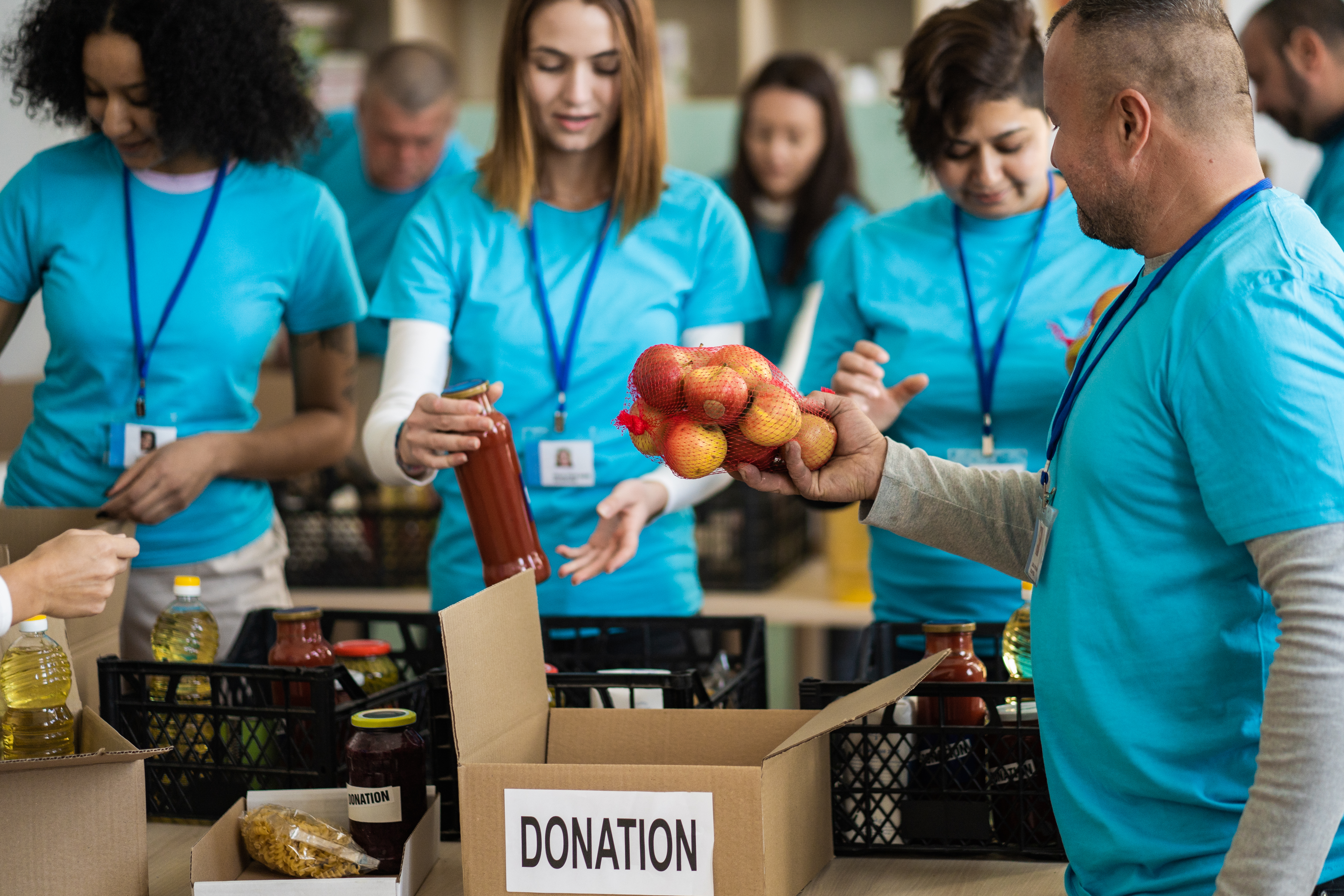 a group of males and females in matching light blue shirts sort produce at a foodbank for a corporate volunteer event with tampawell