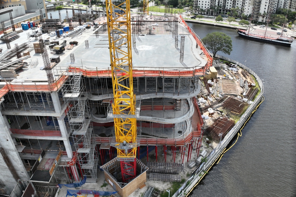 side view of the TGH Taneja Surgical, Neuroscience & Transplant Tower under construction with waterway , pirate ship and residential neighborhood in background