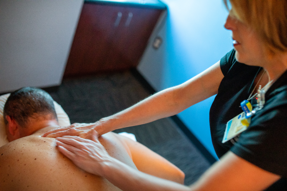 tgh fitness center female massage therapist performing massage therapy on a male patient's back