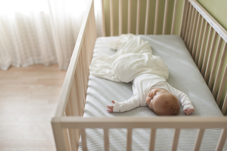 abc of safe sleep image showing a baby sleeping in her crib in a brightly lit nursery
